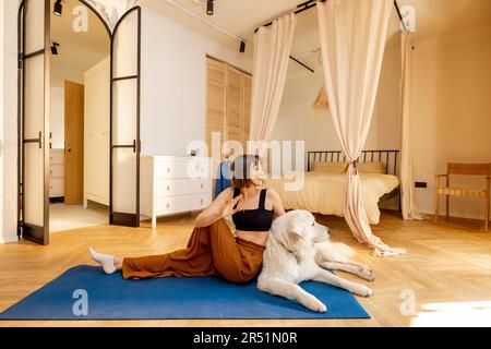 Woman doing yoga with her dog at home Stock Photo