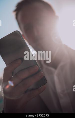 A businessman using his smartphone outdoors, showcasing the seamless integration of technology and mobility in modern professional life. Stock Photo