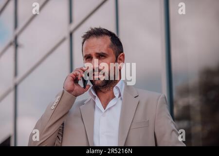 A businessman using his smartphone outdoors, showcasing the seamless integration of technology and mobility in modern professional life. Stock Photo