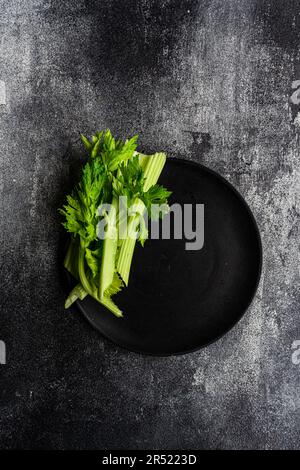 Top view of celery sticks on black plate on concrete dark surface Stock Photo