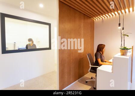Concentrated female in medical uniform sitting at table and browsing laptop while working in modern hospital Stock Photo