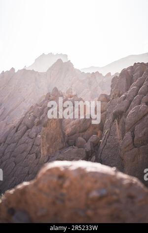 Front view of rough rocky mountains with uneven surface and dry brown stones in daylight on blurred background Stock Photo