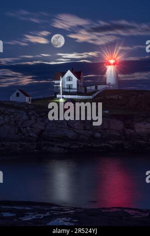 Nubble Hunters Full Moon - The iconic and historic Nubble Lighthouse in Cape Neddick in York, Maine alongside the rising Hunters full moon.   This ima Stock Photo