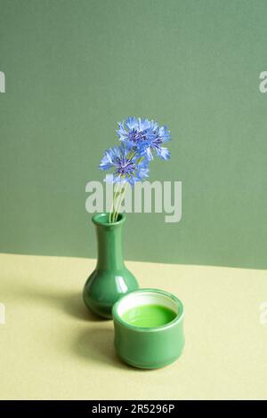 Green tea and vase of purple flower on table. green wall background Stock Photo