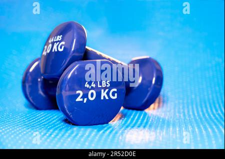 Small blue vinyl dumbbells used for yoga, pilates, and other sports on a mat Stock Photo