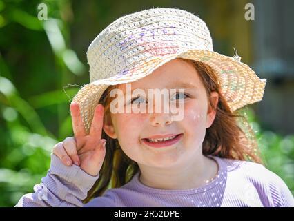 Young girl of 6  years old smiling and wearing a sunhat on a lovely warm day in Spring UK Stock Photo