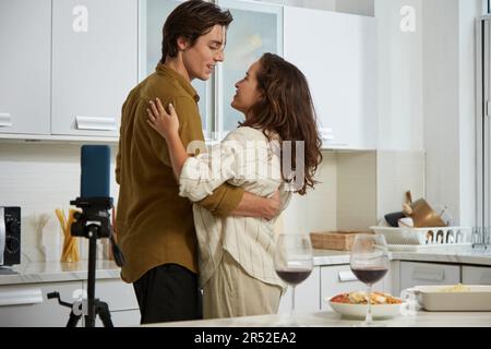 Couple in love filming romantic video of themselves dancing in kitchen Stock Photo