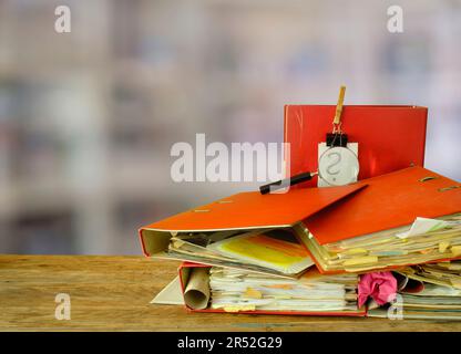 messy file folders, magnifying glass with blurred office in the back, red tape, bureaucracy,office, business concept Stock Photo