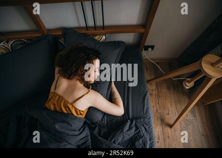 Woman sleeping on side on bed at home Stock Photo