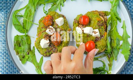 Chef woman hand put a cherry tomato on delicious avocado toast Stock Photo