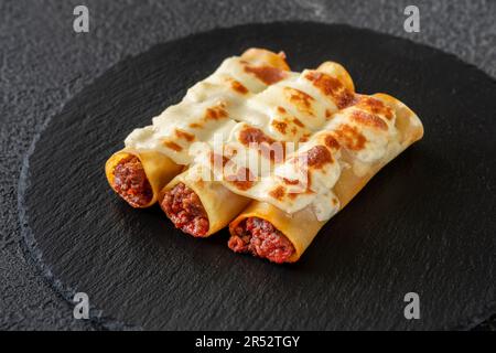 Cannelloni pasta stuffed with bolognese sauce with mozzarella Stock Photo