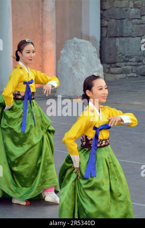 Beautiful women from the Republic of Korea in colorful costumes perform a traditional dance at the XXI International Folklore Festival in the ancient Stock Photo