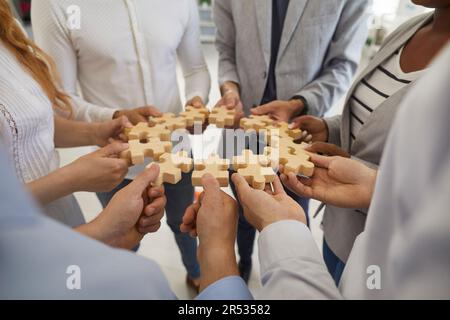 Team of business people forming a circle with jigsaw puzzle parts in their hands Stock Photo