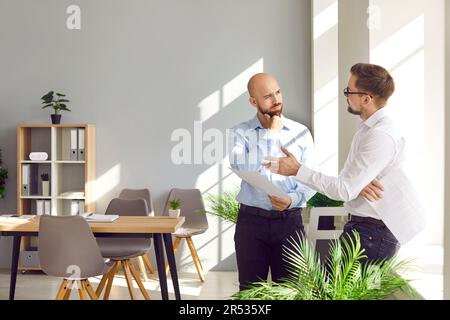 Two business people standing in office near the workplace having discussion and talking on meeting. Stock Photo