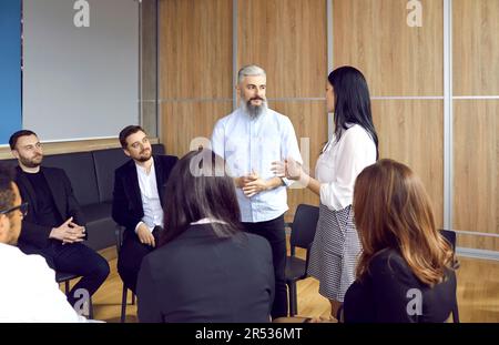 Man and woman discussing new project on office meeting with colleagues during working day. Stock Photo