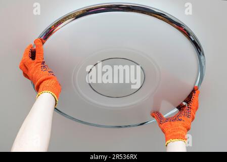 An electrician installs a chandelier on the ceiling.  Stock Photo