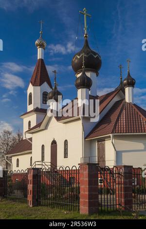 Five-domed temple: five domes,one of which rises above the rest.Brown tent over the bell tower and roof.Mixed eclectic style.White walls, forged fence Stock Photo