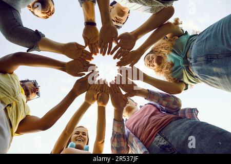 Group of friends stand outdoors making circle with their hands that symbolizes unity. Stock Photo