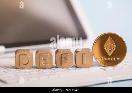 Defi. Golden blocks with Defi inscription, coin Ethereum cryptocurrency on laptop. Stock Photo