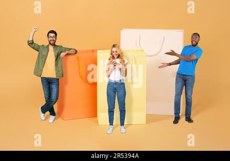 Happy multicultural young friends posing with huge shopping bags Stock Photo