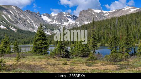 Indian Peaks at Long Lake - A panoramic view of rugged Indian Peaks at shore of Long Lake on a sunny Spring morning. Indian Peaks Wilderness, CO, USA. Stock Photo