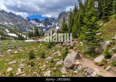 Mountain Trail - Two well-equipped mountaineers hiking on Pawnee Pass Trail towards rugged Indian Peaks on a sunny Summer day. Indian Peaks Wilderness. Stock Photo
