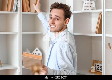 Young man taking books from shelf at home Stock Photo