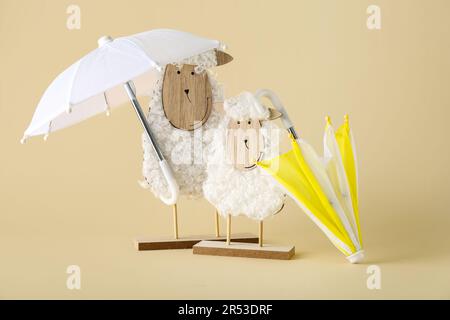 Creative composition with wooden toys sheep and mini umbrellas on beige background Stock Photo