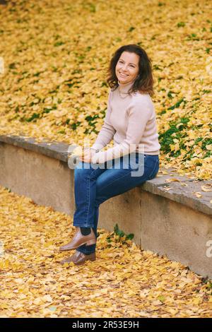 Autumn portrait of beautiful mature woman, relaxing in golden fall park Stock Photo