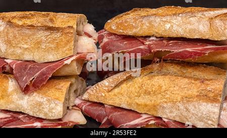 Freshly made Iberico Spanish ham baguette sandwiches in a delicatessen Stock Photo