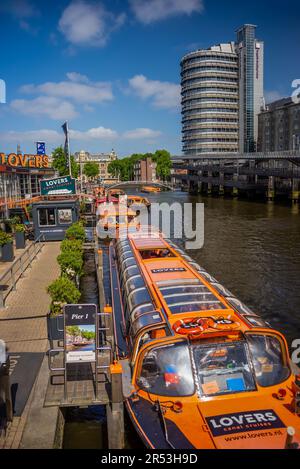 26 May, 2023, AMSTERDAM, NETHERLANDS, Lovers Canal Cruises boats on the cruise dock, near the Amsterdam Central Station Stock Photo