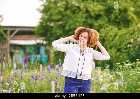 Outdoor portrait of beautiful 50 year old woman enjoying nice day in flower park or garden, happy and healthy lifestyle Stock Photo