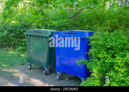 Two plastic trash containers. The containers are located in the city park. Separate sorting of waste. Responsible attitude to the environment. Zero wa Stock Photo