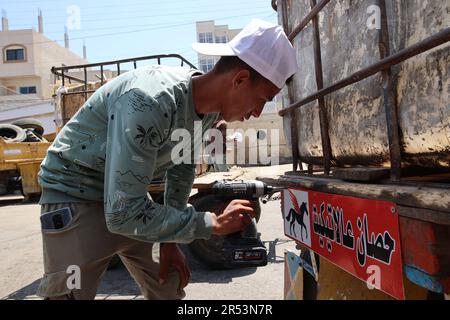 A Palestinian activist puts sign on a cart as he conducts the initiative of 'Horse Etiquette' in Deir al-Balah City central Gaza Strip. Palestinian activists are implementing an initiative called 'A Horse on Etiquette'. They put diapers for animals, which are implemented by the Seeds Theater Association for Culture and Arts, funded by the Abdul Mohsen Qattan Cultural Foundation, which targets animals that pull carts in order to reduce street pollution due to the excrement of these animals to preserve the environment in Deir al-Balah City central Gaza Strip. Stock Photo