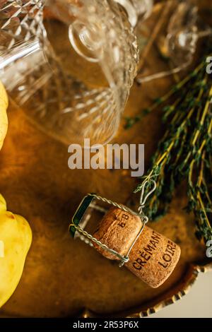 Cremate loire champagne cork and cage on brass tray with bunch of thyme, coupe glass, fruit Stock Photo