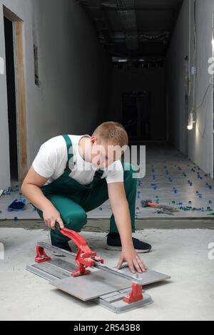 Worker using manual tile cutter in room Stock Photo