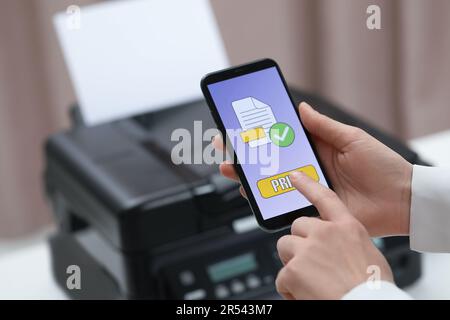 Man using printer management application on mobile phone indoors, closeup and space for text Stock Photo
