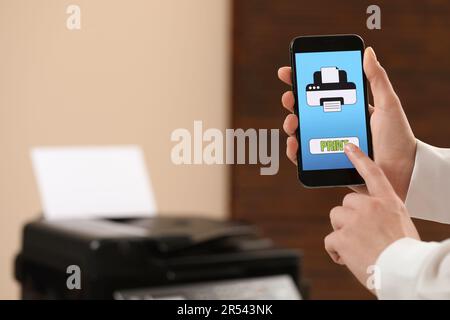 Man using printer management application on mobile phone indoors, closeup and space for text Stock Photo