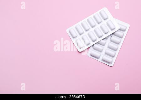 Blisters with chewing gums on pink background, flat lay. Space for text Stock Photo