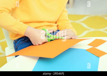 Preparing for Halloween. Teenage kid hands cutting black paper bat