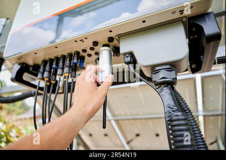 Point of view on configuring PV solar panel. Professional worker turning on solar inverter. Pov man preparing battery for work. Stock Photo