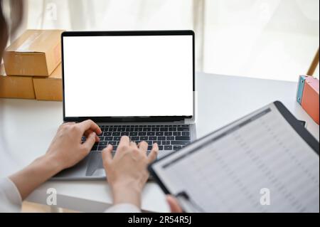 Close-up image of a female online business owner or website admin confirming customer orders on the website and checking product stocks through her la Stock Photo