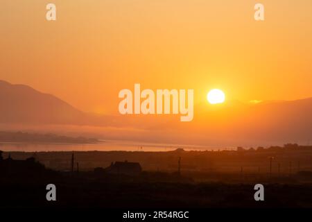 Portmagee, County Kerry, Ireland. 1st June 2023.  Glorious golden sunrise and jet trail over Portmagee Channel to herald in the first day of June. Photo Credit: Stephen Power / Alamy Live News Stock Photo