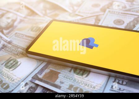 Paypal logo displayed on smartphone on top of pile of money. Business profit concept Stock Photo