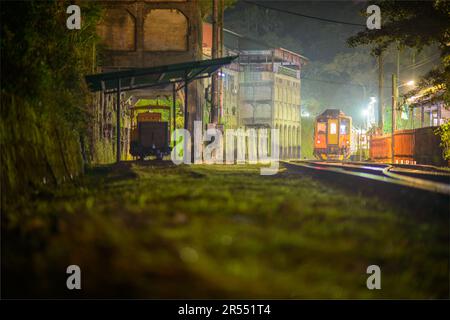 A yellow diesel train pulls into the station at night with lights on. Jingtong Station is the last station of Pingxi Line, which was built in 1929. Stock Photo