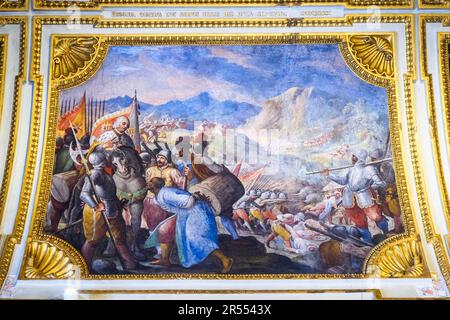 Painted ceiling framed by gilded stucco mouldings and inscriptions depicting the battle against the Moors on the Alpuxarras Mountains - The ambassador's Hall in the Royal Palace of Naples that In 1734 became the royal residence of the Bourbons - Naples, Italy Stock Photo