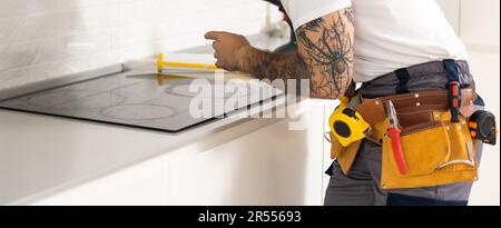 craftsman installs hob in kitchen. Household Appliance Installation Services Concept Stock Photo