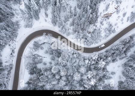 Truck minibus moving during snowfall on winding and curving, meandering mountain road Stock Photo