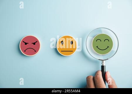 Magnifier in hand focuses on selected happy smiley face icon Stock ...