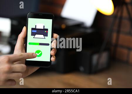 Man using printer management application on mobile phone indoors, closeup and space for text Stock Photo